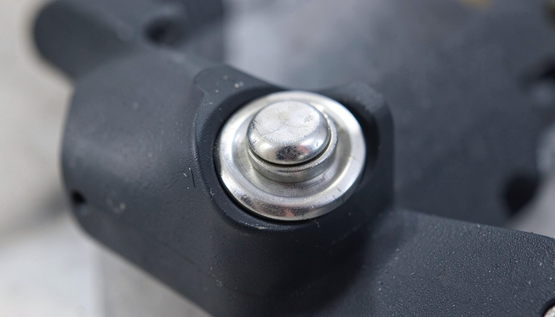 Close-up of a quick-change tool interface mechanism with metallic collar and dark composite body